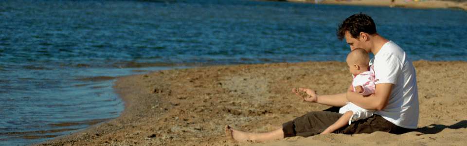 Man with young child at a sandy shore